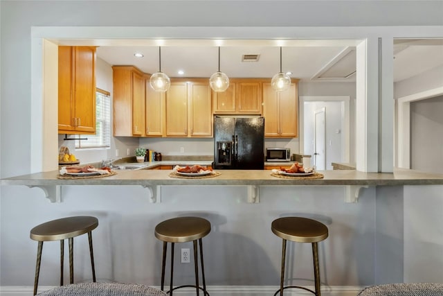 kitchen with stainless steel microwave, visible vents, pendant lighting, a peninsula, and black fridge with ice dispenser