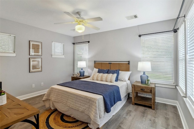 bedroom featuring ceiling fan, wood finished floors, visible vents, and baseboards