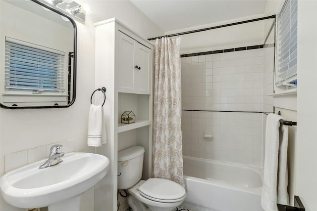 bathroom featuring toilet, shower / bath combo with shower curtain, and a sink