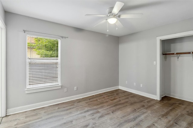 unfurnished bedroom featuring a ceiling fan, wood finished floors, baseboards, and a closet