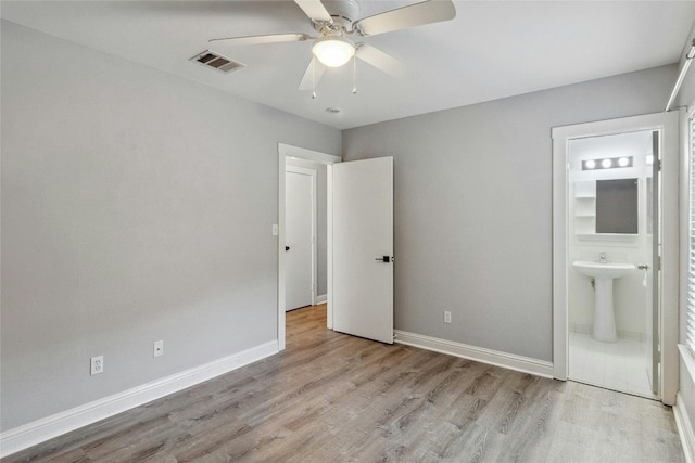 unfurnished bedroom with visible vents, baseboards, light wood-style floors, ensuite bath, and a ceiling fan