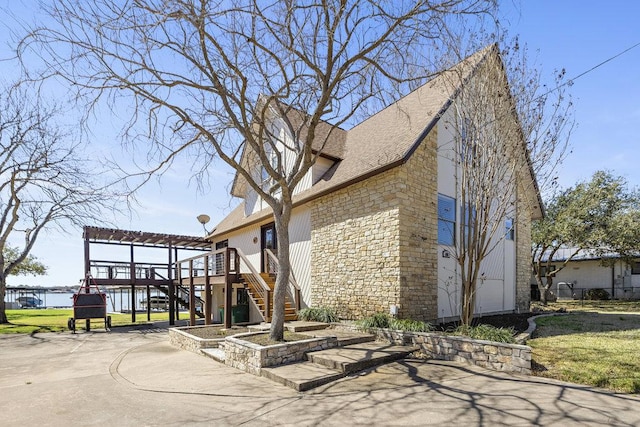 exterior space featuring a pergola, stone siding, stairway, a shingled roof, and a wooden deck