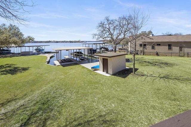 dock area featuring boat lift, a water view, and a lawn