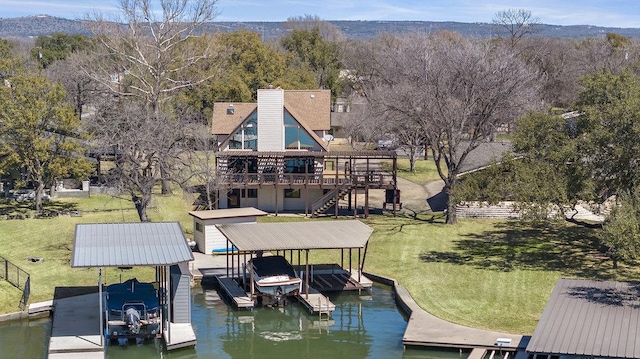 dock area with a deck with water view, boat lift, stairs, and a lawn