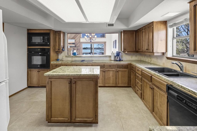 kitchen featuring visible vents, a center island, an inviting chandelier, black appliances, and a sink