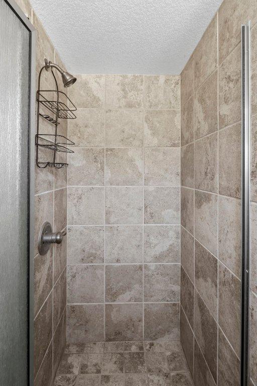 full bath with a stall shower and a textured ceiling