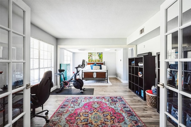 office featuring visible vents, baseboards, a textured ceiling, and wood finished floors