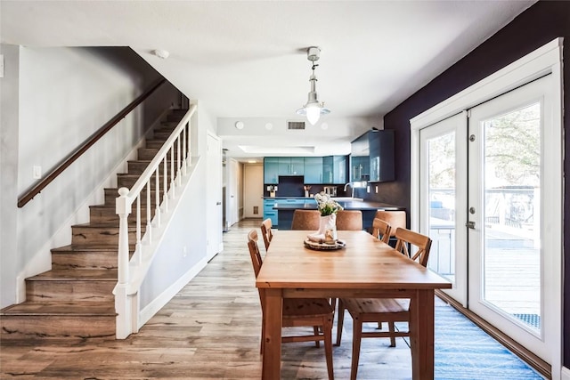 dining room with visible vents, light wood-style flooring, french doors, and stairway