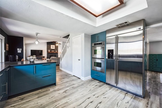 kitchen featuring visible vents, blue cabinetry, dark countertops, stainless steel appliances, and ceiling fan