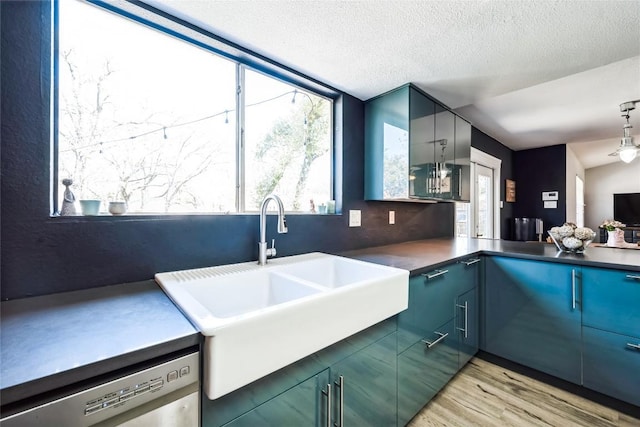 kitchen featuring blue cabinetry, a sink, light wood-style floors, a textured ceiling, and dishwasher