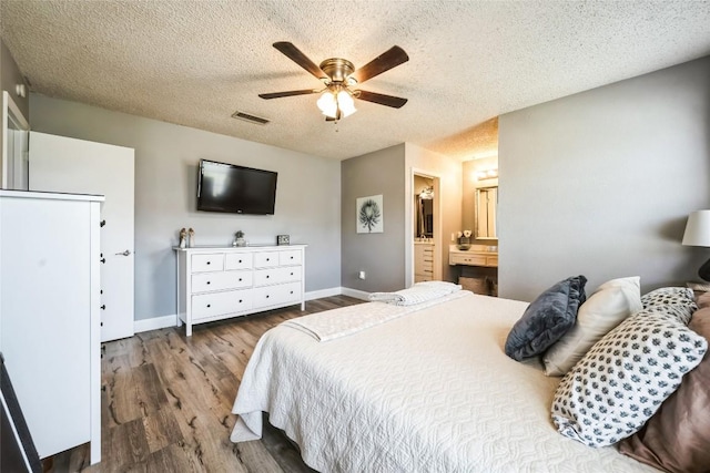 bedroom with baseboards, wood finished floors, visible vents, and a textured ceiling