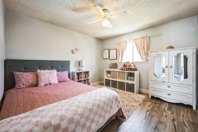 bedroom featuring a textured ceiling, a ceiling fan, baseboards, and wood finished floors