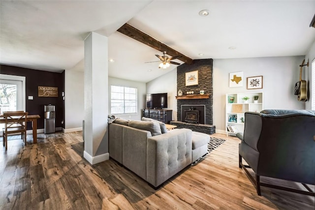 living room featuring a ceiling fan, lofted ceiling with beams, wood finished floors, a large fireplace, and baseboards