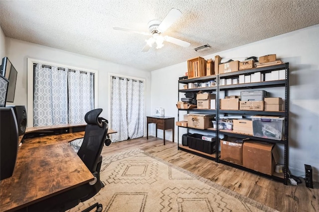 office with visible vents, a textured ceiling, wood finished floors, and a ceiling fan