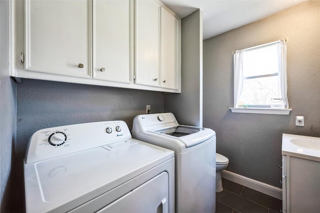 laundry room featuring dark tile patterned flooring, baseboards, laundry area, separate washer and dryer, and a sink