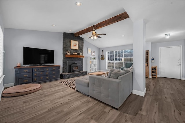 living area featuring a large fireplace, baseboards, lofted ceiling with beams, wood finished floors, and a ceiling fan