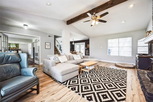 living area with wood finished floors, visible vents, lofted ceiling with beams, ceiling fan, and stairs