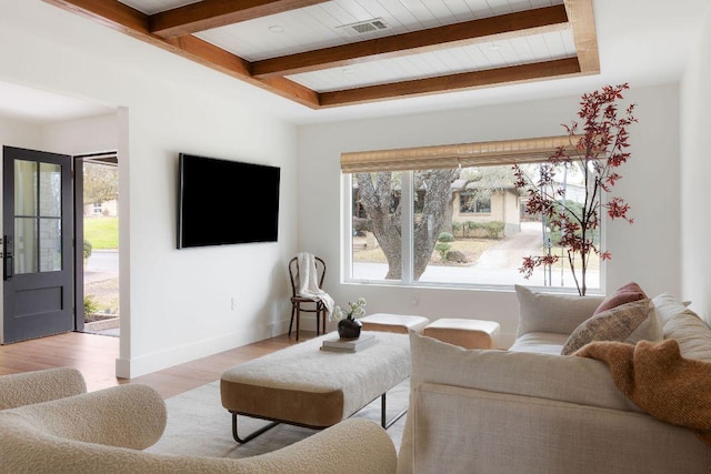 living room with visible vents, beamed ceiling, light wood-type flooring, and baseboards