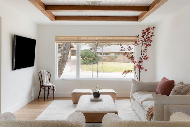 living room with beamed ceiling, light wood-style flooring, visible vents, and baseboards