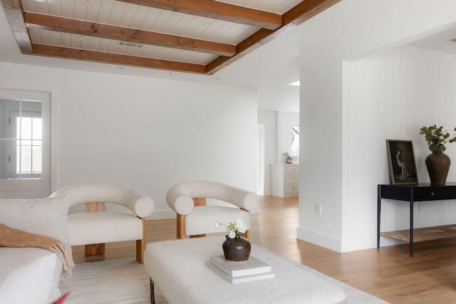 sitting room featuring beam ceiling, wood finished floors, baseboards, and wooden ceiling