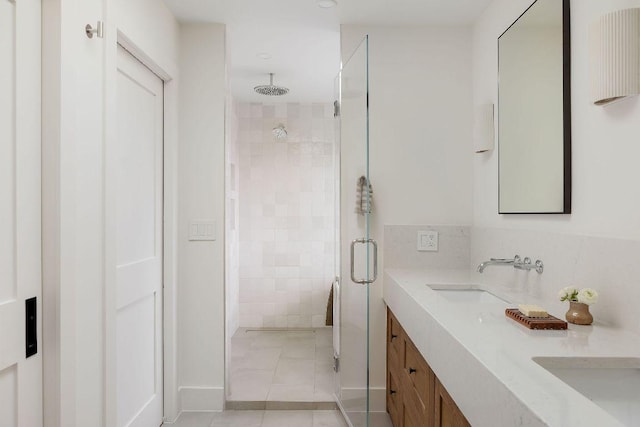 full bath featuring a shower stall, double vanity, decorative backsplash, tile patterned floors, and a sink