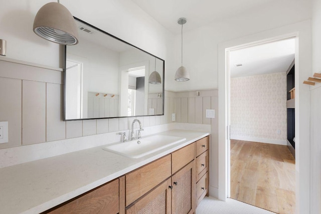 bathroom with visible vents, wood finished floors, wallpapered walls, baseboards, and vanity