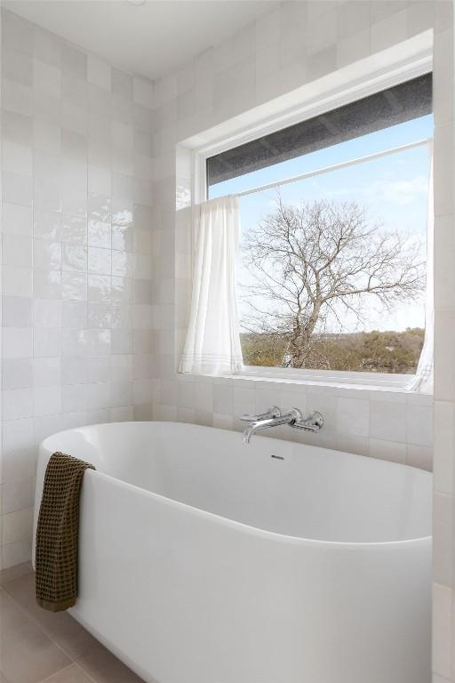 bathroom featuring a freestanding bath, tile walls, and tile patterned flooring