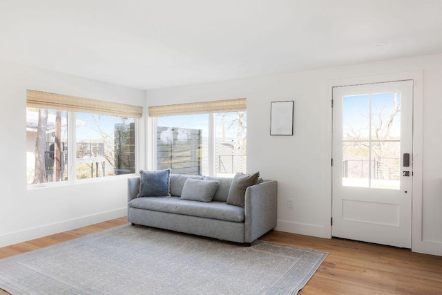 living area featuring plenty of natural light, light wood-style floors, and baseboards