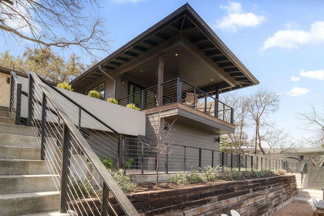 rear view of house with a balcony, stairway, and fence