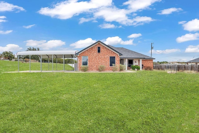 rear view of property with brick siding, a carport, a lawn, and fence