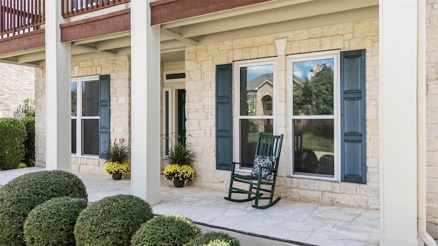 doorway to property with a porch and stone siding