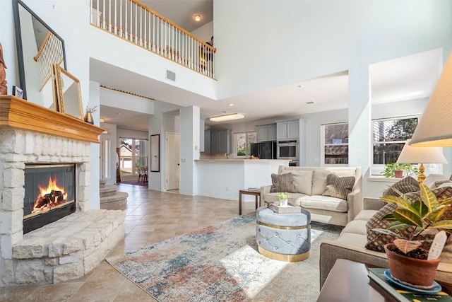 living room with light tile patterned floors, visible vents, baseboards, and a stone fireplace