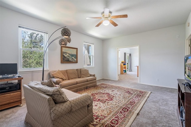 living room featuring light carpet, baseboards, and a ceiling fan