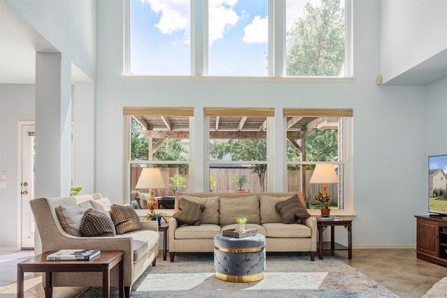 tiled living area featuring a healthy amount of sunlight and a towering ceiling