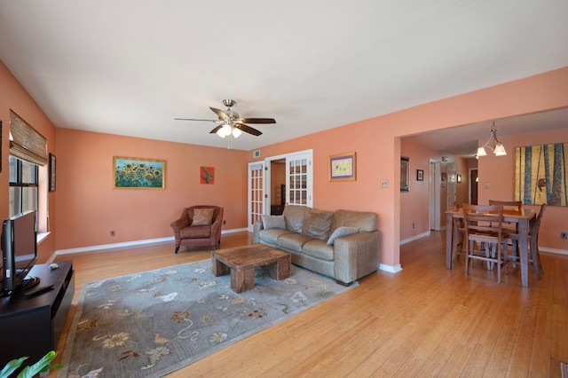 living area featuring wood finished floors, baseboards, french doors, and ceiling fan