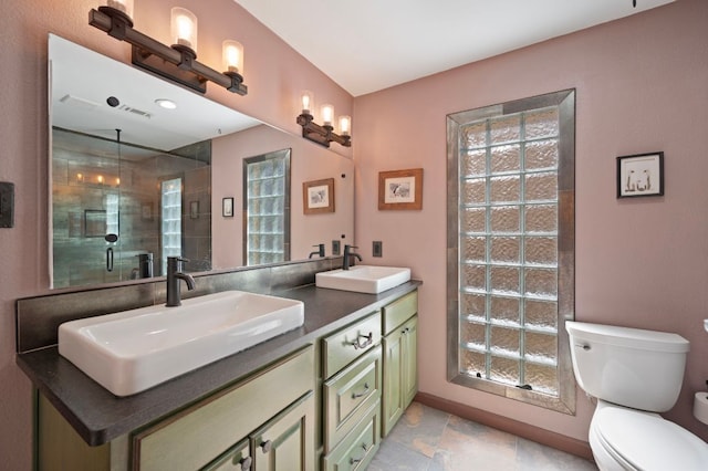 full bathroom with double vanity, toilet, tiled shower, and a sink