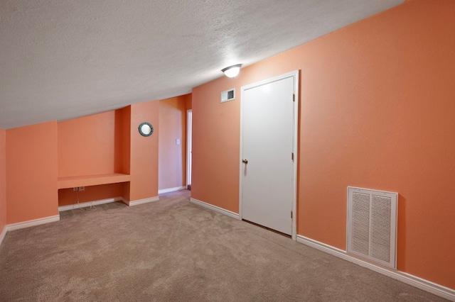 carpeted empty room with visible vents, a textured ceiling, and baseboards