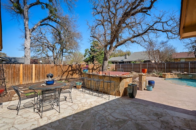 view of patio / terrace with outdoor dining space, a fenced backyard, a fenced in pool, and outdoor dry bar