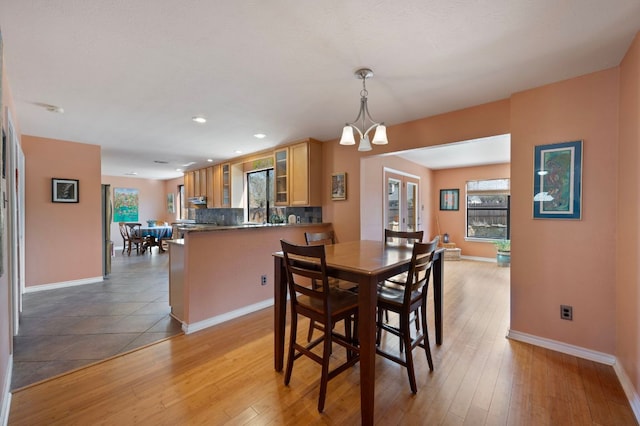 dining area featuring an inviting chandelier, light wood-style flooring, and baseboards