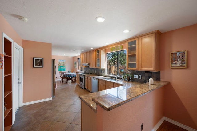 kitchen with stone countertops, plenty of natural light, tasteful backsplash, and appliances with stainless steel finishes