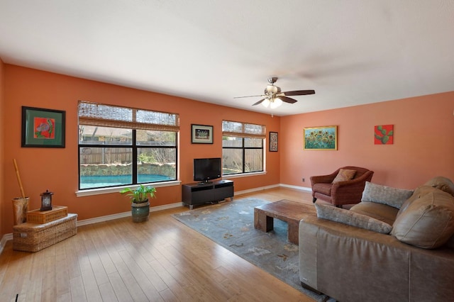 living room featuring baseboards, wood finished floors, and a ceiling fan