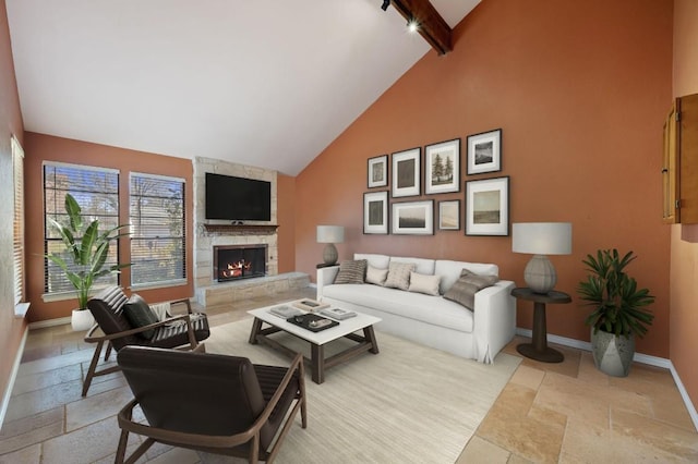 living area with beamed ceiling, high vaulted ceiling, stone tile floors, a stone fireplace, and baseboards