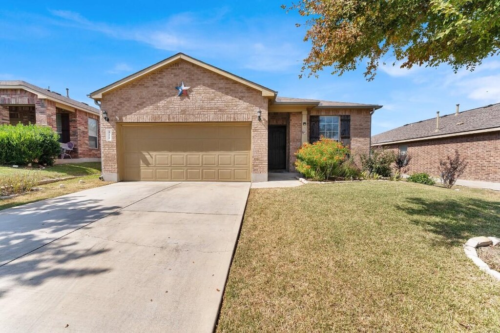 ranch-style home featuring brick siding, a garage, concrete driveway, and a front yard