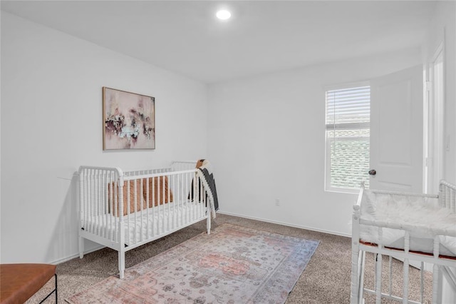 carpeted bedroom featuring a crib, recessed lighting, and baseboards