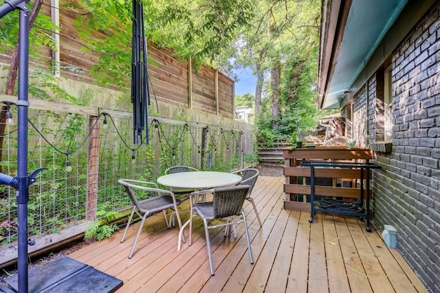 wooden terrace with outdoor dining space and fence