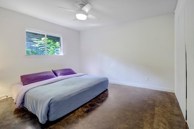 bedroom featuring a ceiling fan, concrete floors, and baseboards