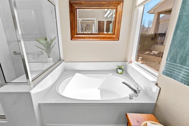 bathroom featuring a garden tub and a textured wall