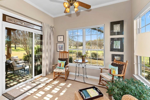 living area with crown molding, baseboards, and ceiling fan