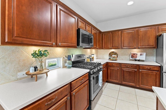 kitchen with light countertops, backsplash, light tile patterned flooring, and appliances with stainless steel finishes