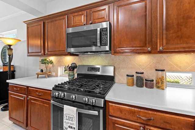 kitchen featuring backsplash, crown molding, light countertops, appliances with stainless steel finishes, and brown cabinetry